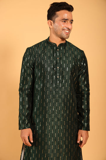 This Mehendi Green silk-blend kurta is designed for comfort and elegance, featuring tone-on-tone threadwork with sequin detailing that runs horizontally for a striking yet subtle effect. Ideal for pujas, haldi, and festive occasions, the kurta is adorned with meenakari buttons along the front placket and finished with a mandarin collar. The knee-length hem adds to its traditional charm, making it a versatile choice for special celebrations.