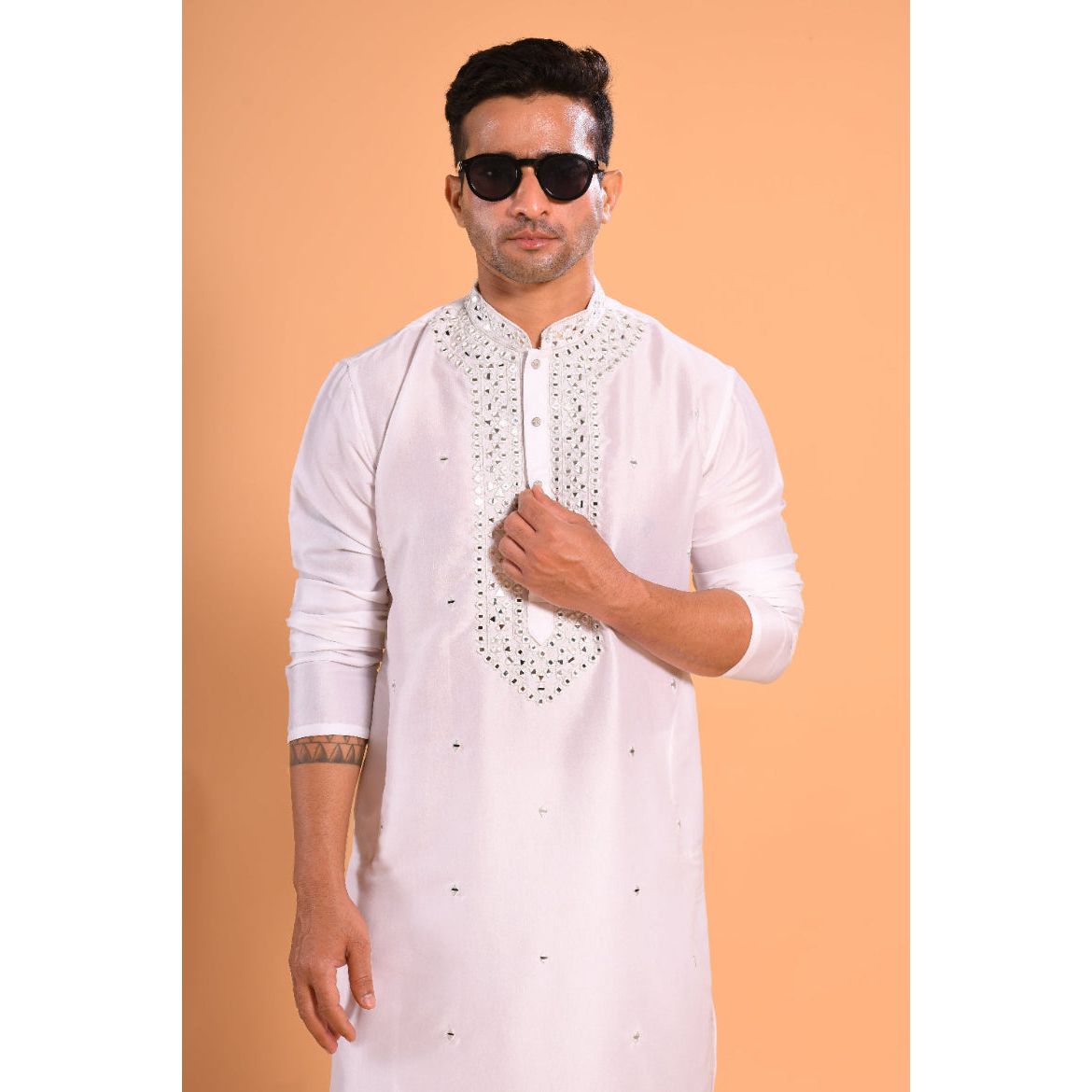 A man wearing a white viscose silk kurta with real mirror work and a mandarin collar, featuring a slim fit cut and full sleeves.