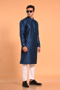 This Teal Blue silk-blend kurta is designed for comfort and elegance, featuring tone-on-tone threadwork with sequin detailing that runs horizontally for a striking yet subtle effect. Ideal for pujas, haldi, and festive occasions, the kurta is adorned with meenakari buttons along the front placket and finished with a mandarin collar. The knee-length hem adds to its traditional charm, making it a versatile choice for special celebrations.