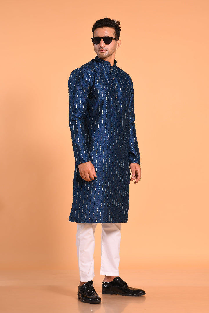 This Teal Blue silk-blend kurta is designed for comfort and elegance, featuring tone-on-tone threadwork with sequin detailing that runs horizontally for a striking yet subtle effect. Ideal for pujas, haldi, and festive occasions, the kurta is adorned with meenakari buttons along the front placket and finished with a mandarin collar. The knee-length hem adds to its traditional charm, making it a versatile choice for special celebrations.