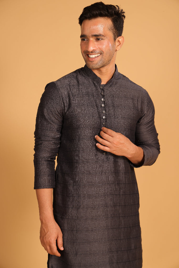 This charcoal gray kurta combines subtle elegance with intricate detailing. Made from a soft, smooth viscose blend, this charcoal gray kurta offers a soft and smooth feel that is gentle on the skin. The intricate all-over threadwork adds texture and detail to the classic design, making it an excellent choice for both formal and festive occasions. The kurta features a mandarin collar and a front placket with meenakari metal buttons, bringing a refined touch to its sleek silhouette.&nbsp;