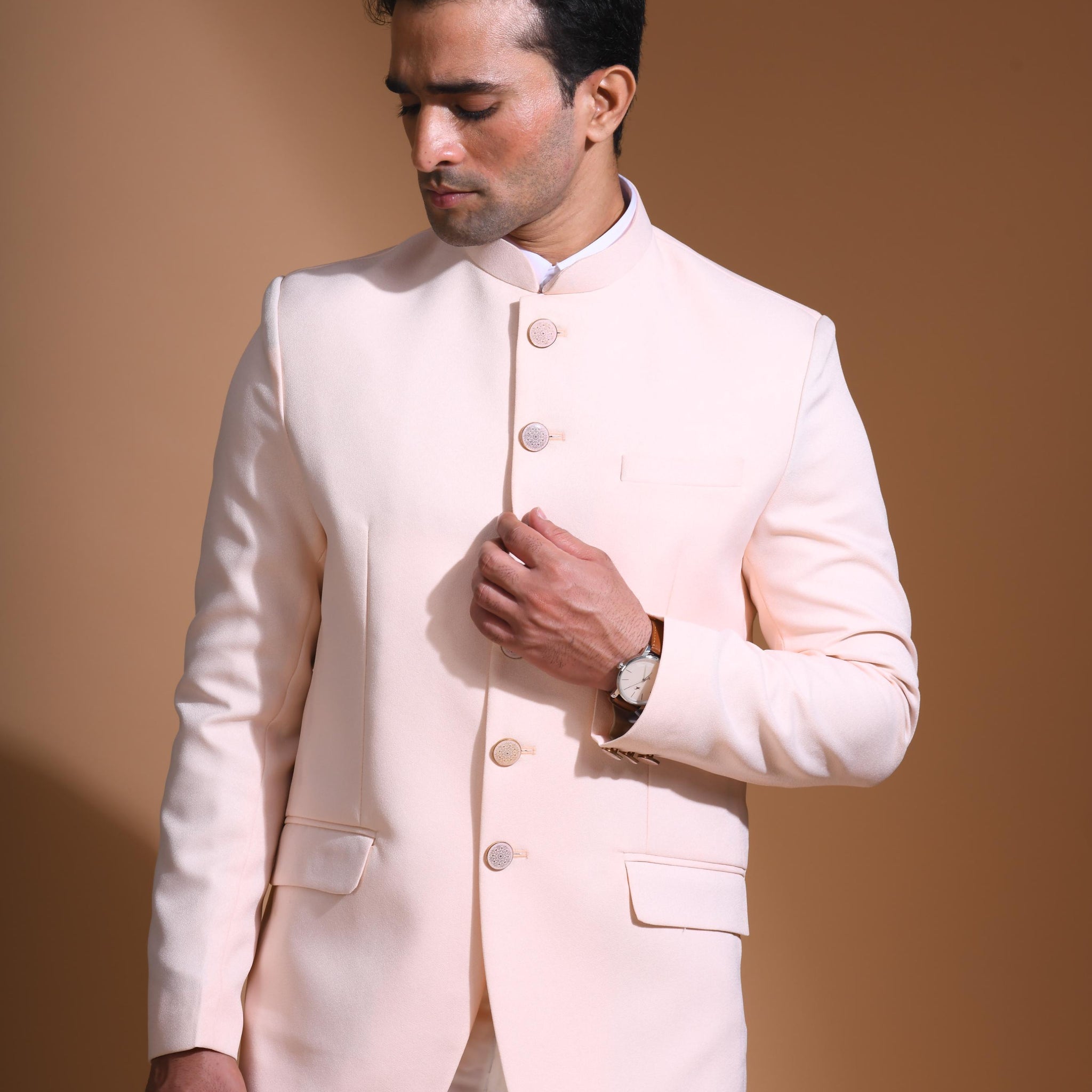 The Light Pink textured bandhgala is designed for those who value timeless elegance and craftsmanship. Made from premium textured suiting fabric, it offers a refined feel and structured drape that enhances your look effortlessly. The bandhgala is accented with 6 contrasting meenakari metal buttons, providing a subtle yet distinct touch of detail. The interior features a premium jacquard lining that ensures both comfort and sophistication.