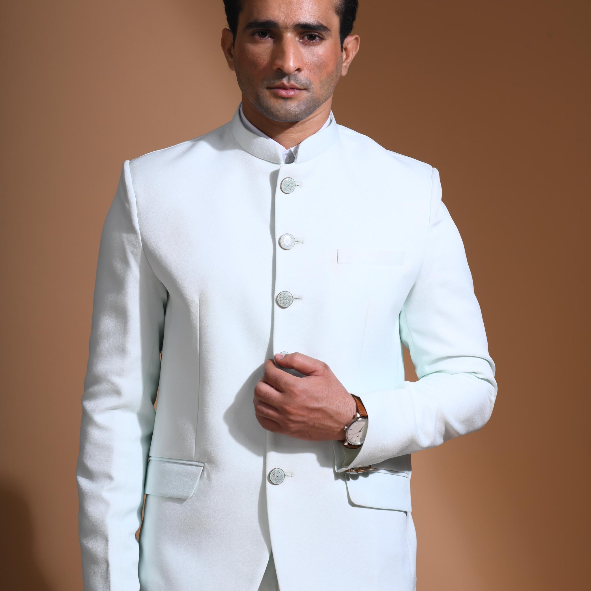 The Cyan Blue textured bandhgala is designed for those who value timeless elegance and craftsmanship. Made from premium textured suiting fabric, it offers a refined feel and structured drape that enhances your look effortlessly. The bandhgala is accented with 6 contrasting meenakari metal buttons, providing a subtle yet distinct touch of detail. The interior features a premium jacquard lining that ensures both comfort and sophistication.